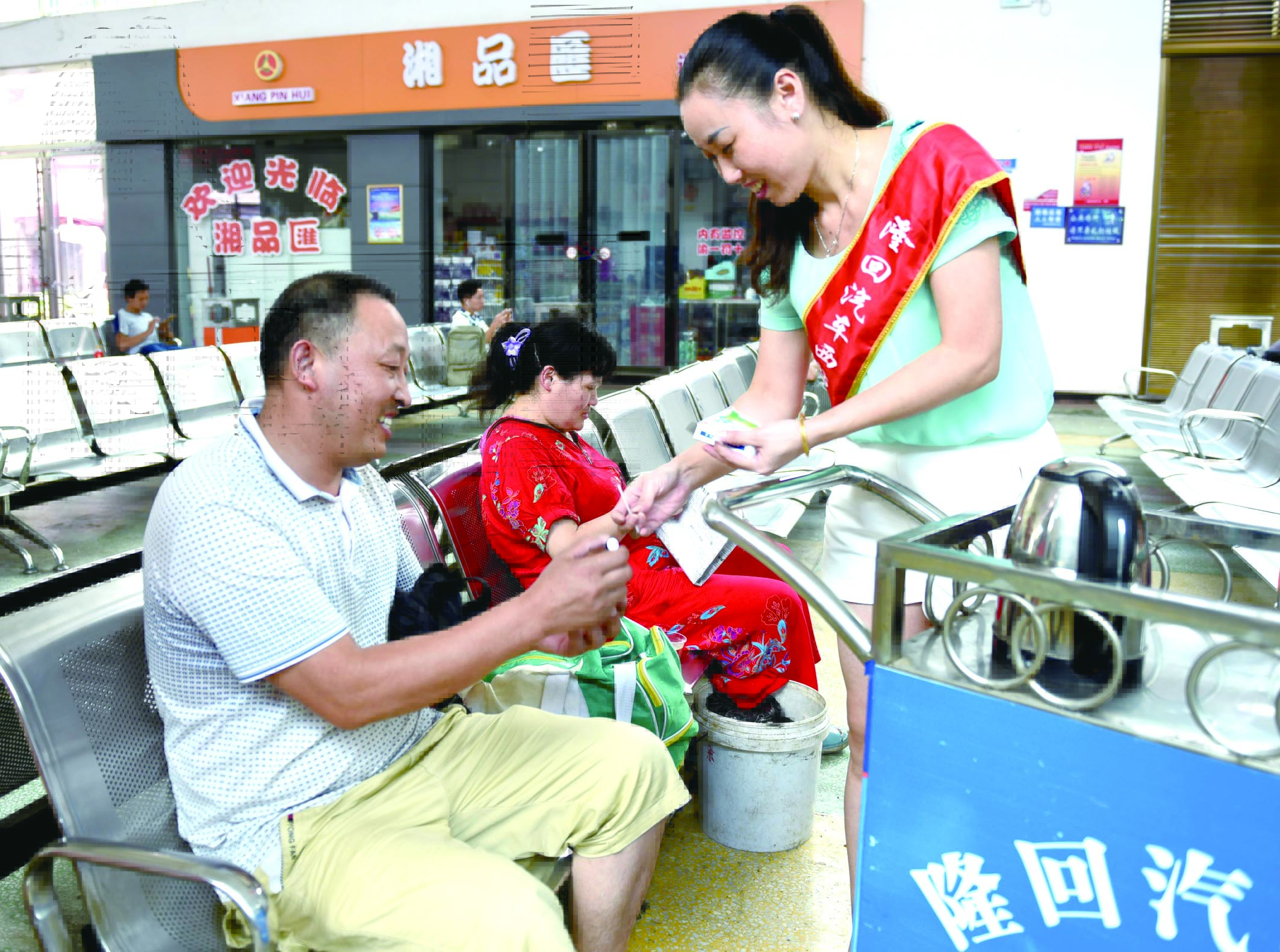 隆回分公司汽車西站工作人員正在為旅客免費贈送藿香正氣水。